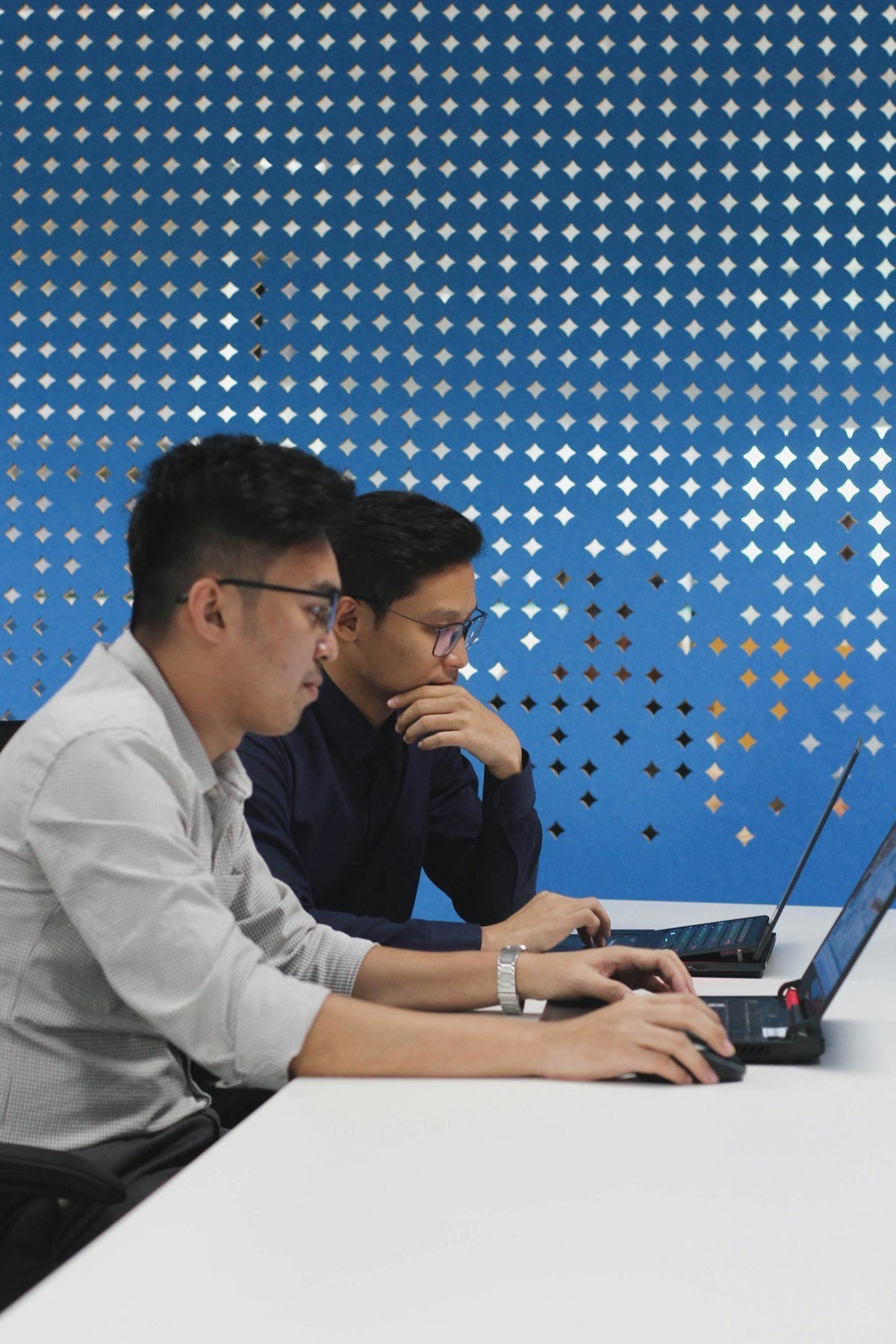 Two analysts reviewing an automated workflow on their laptops