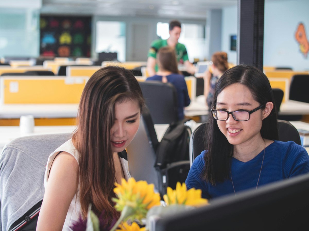 Two colleagues working together at a screen in an open office