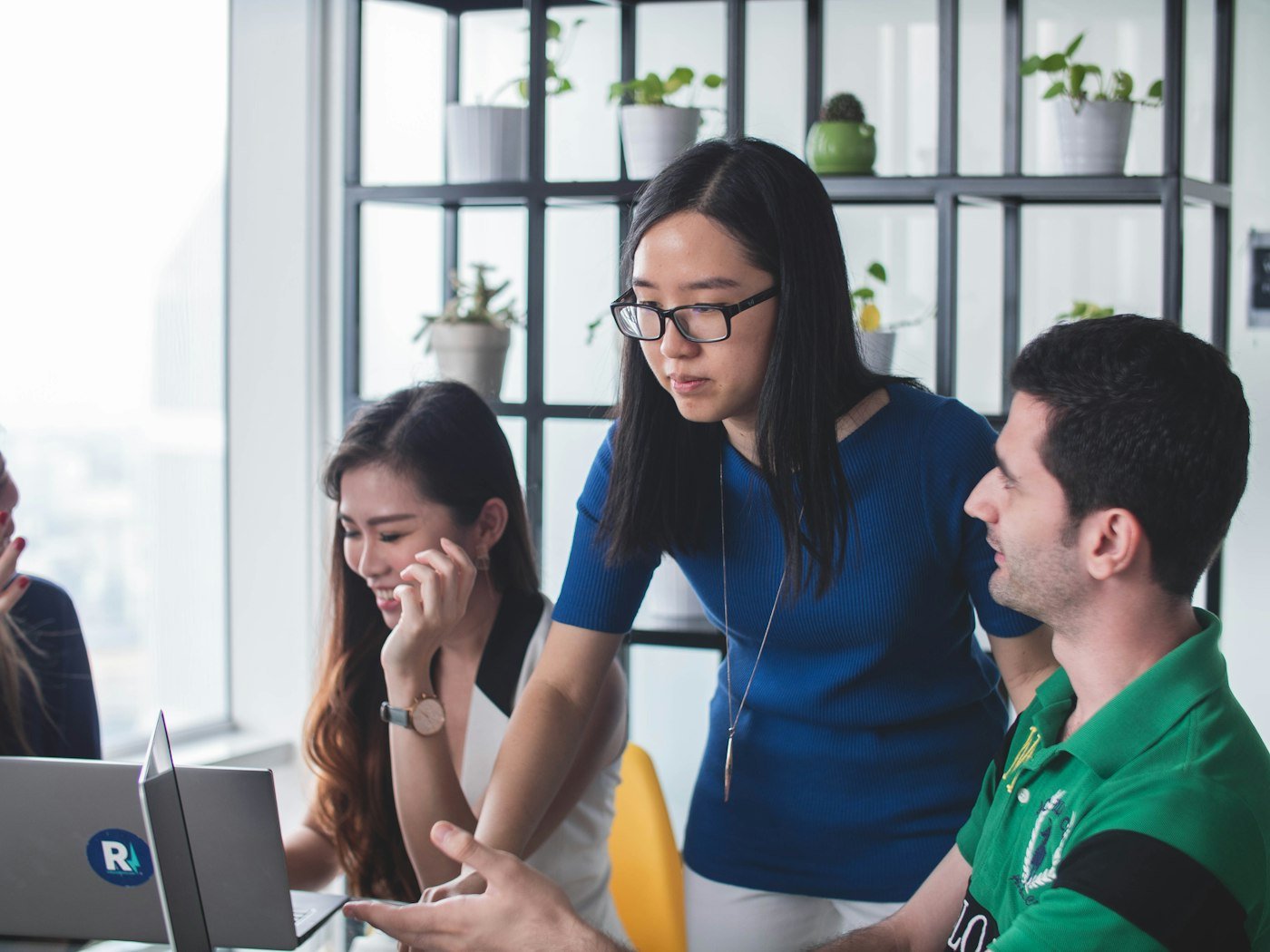 A consultant working through a plan with a client team around a laptop